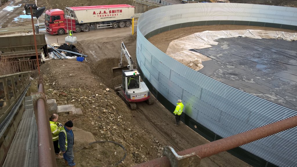 Photo of construction workers on a site installing a tank