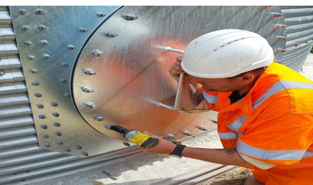 man in his vis with drill sealing a door on a steel water tank 