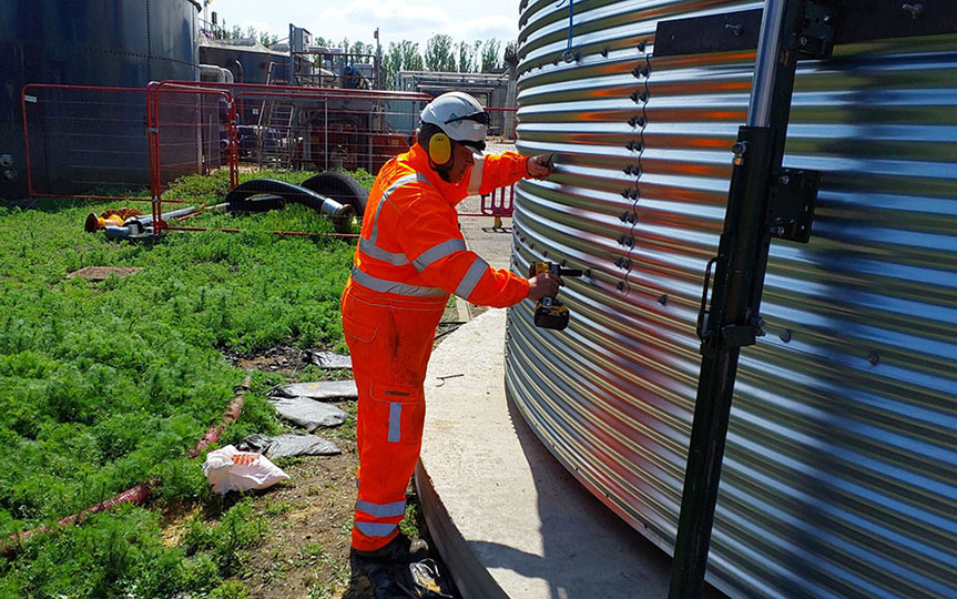 man in his vis securing bolts to a steel water tank 